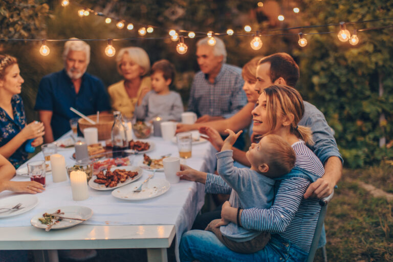Gezellig tuinfeest met familie aan lange tafel in de tuin tijdens een warme zomeravond