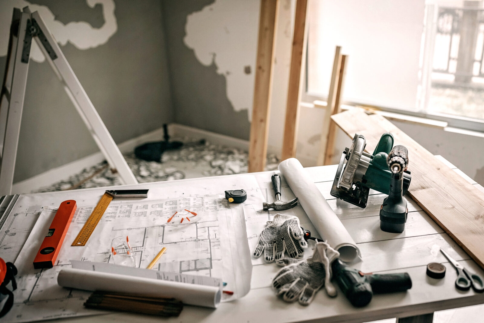 Voorbereiding van een verbouwing met bouwtekening, gereedschap en materialen op tafel