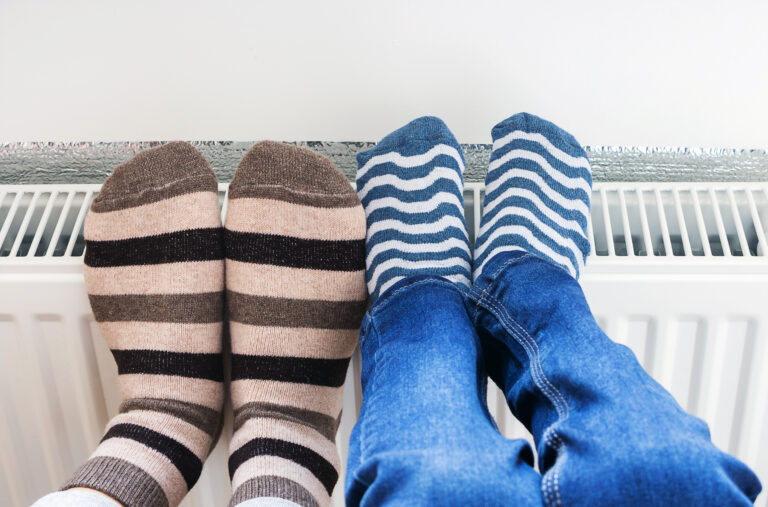Voeten op radiator in woonkamer als symbool voor comfort en warmtepompverwarming