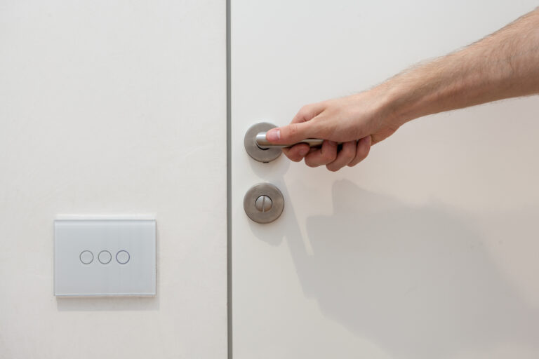 Hand die moderne touchschakelaar bedient naast voordeur in strak interieur