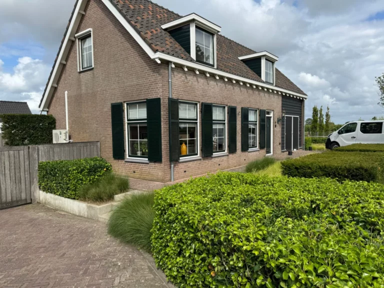 Buitenluiken aan de gevel van een vrijstaande woning met groene raamluiken