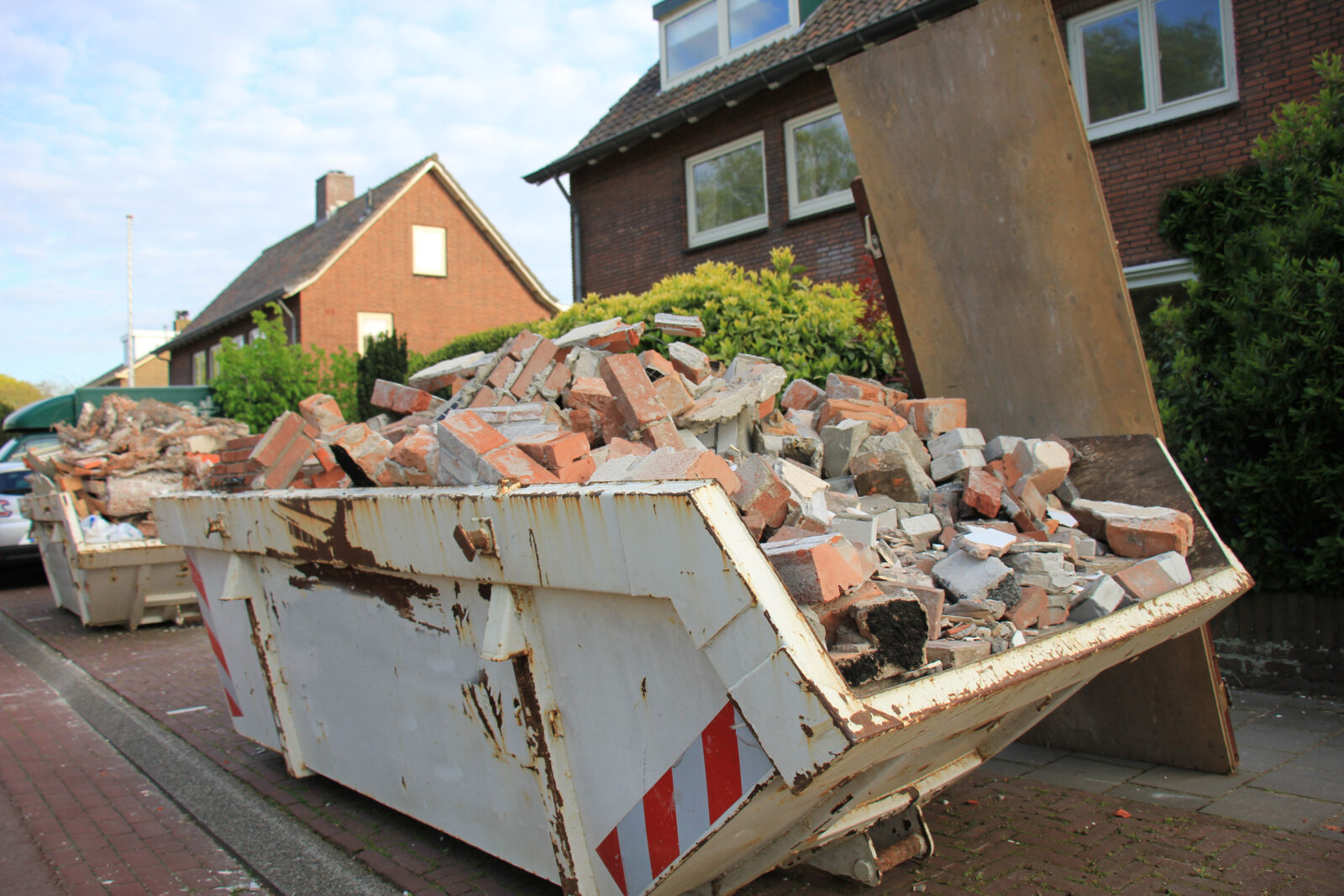 Puincontainer met bakstenen en sloopafval bij woningrenovatie
