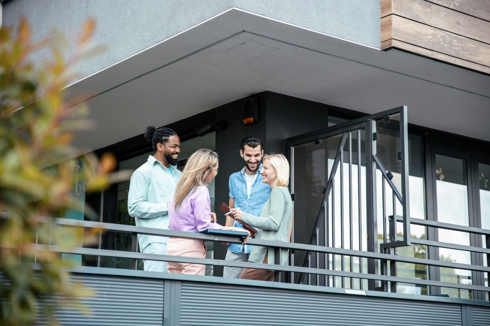 Bewoners van een appartementencomplex in gesprek op een balkon over VvE beheer en onderhoud