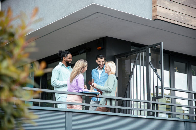 Bewoners van een appartementencomplex in gesprek op een balkon over VvE beheer en onderhoud