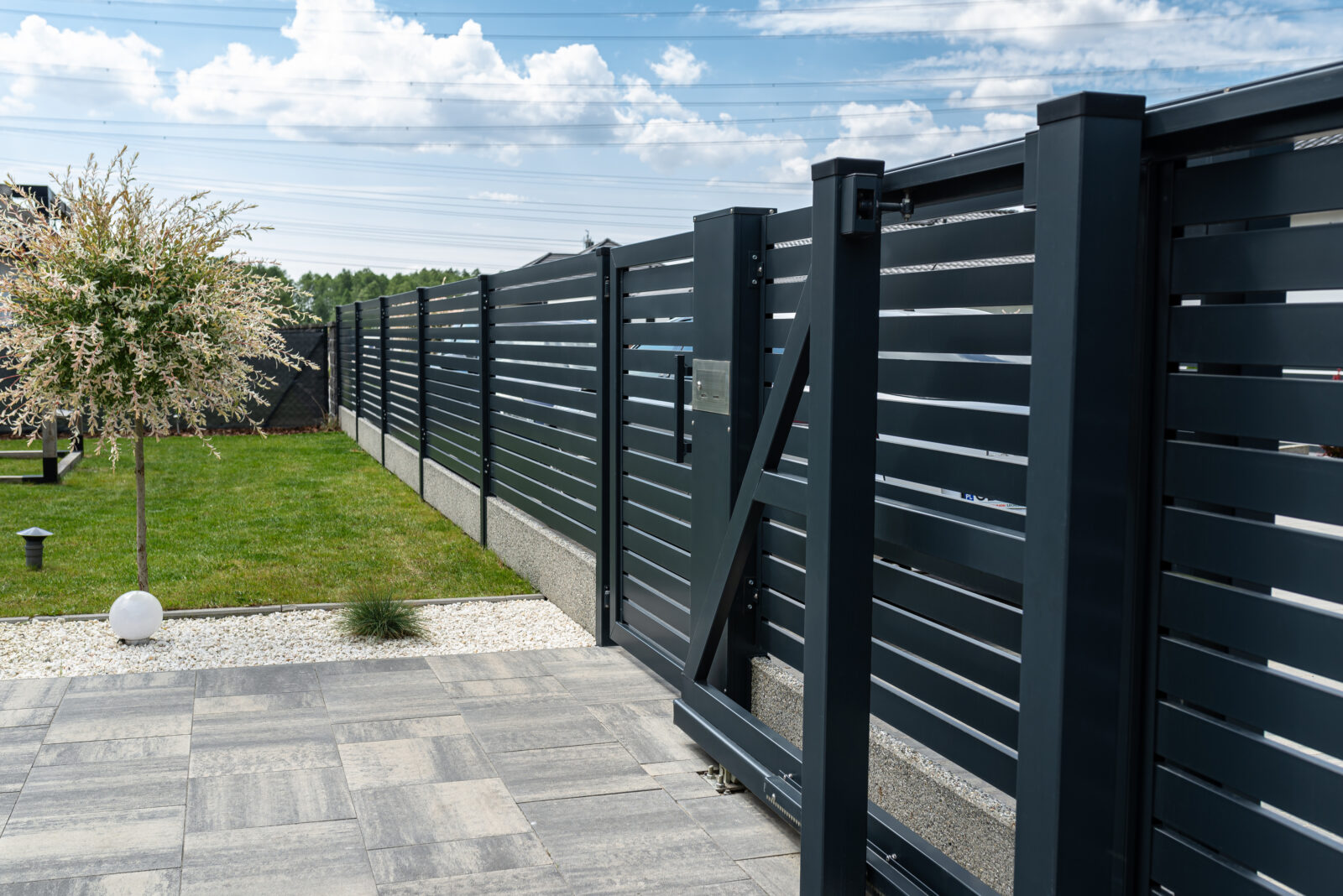 Moderne zwarte lamellen schutting in een strakke achtertuin met terras en gazon