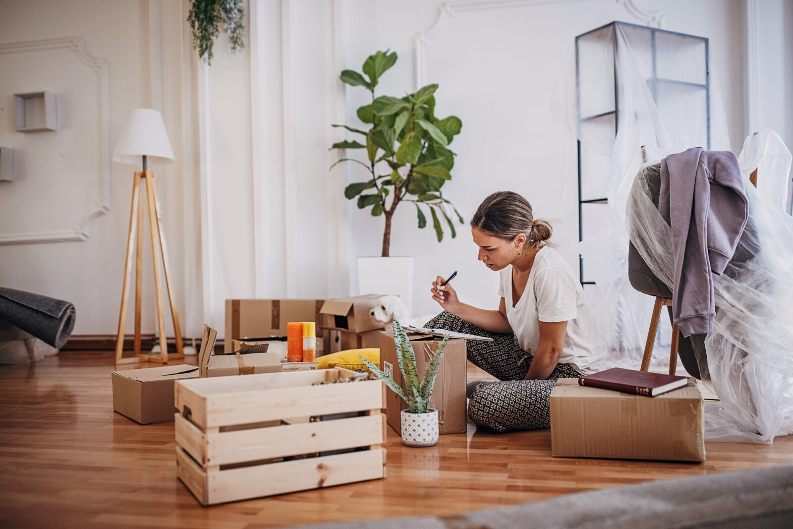 Vrouw maakt een lijst en labelt verhuisdozen tijdens het inpakken voor een verhuizing