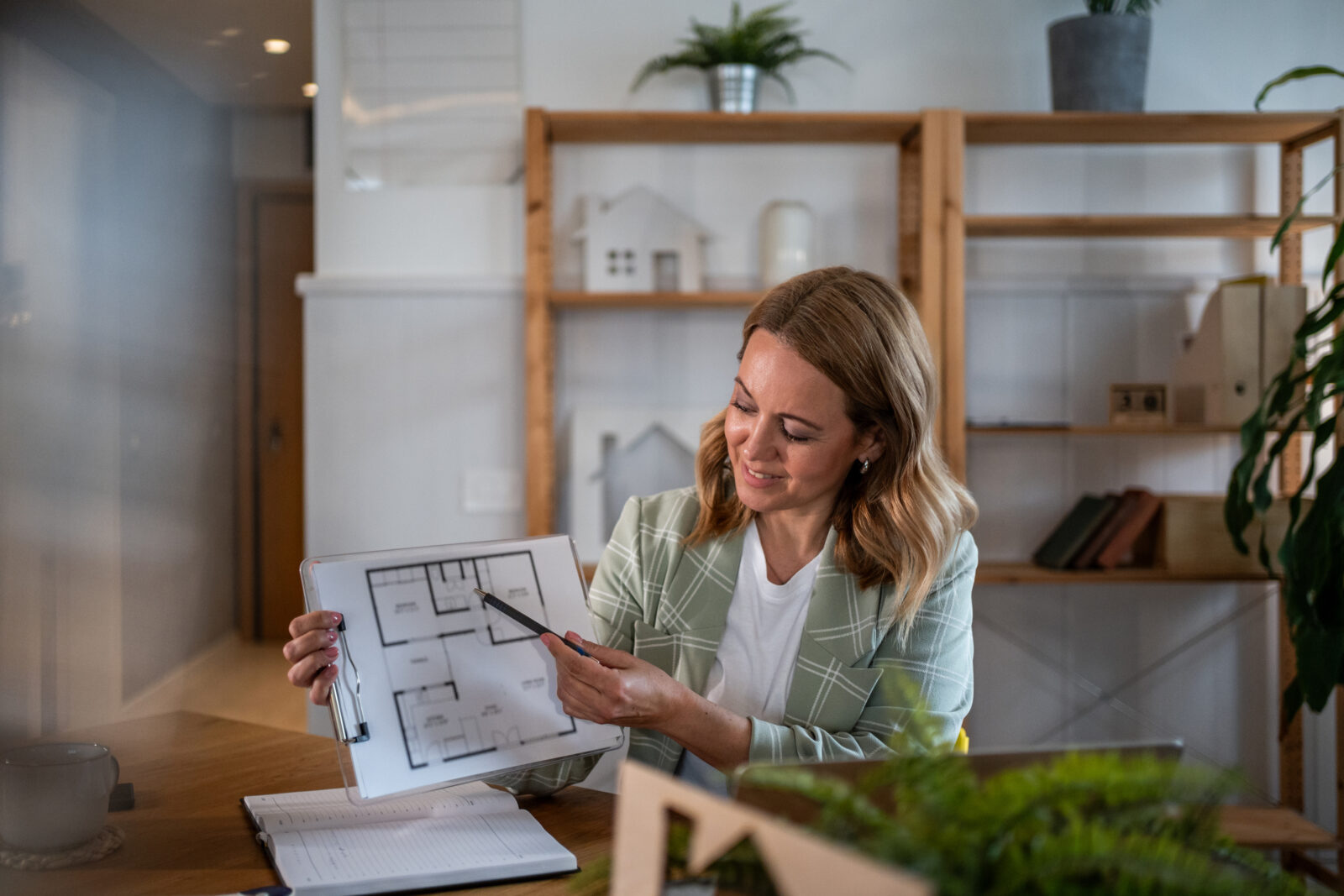 Vrouw aan tafel bekijkt plattegrond van woning in lichte woonkamer