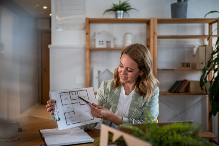 Vrouw aan tafel bekijkt plattegrond van woning in lichte woonkamer