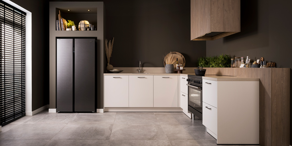 Moderne hoekkeuken met vrijstaande koelkast en ingebouwde oven, voorbeeld van praktische plaatsing van witgoed in de ruimte