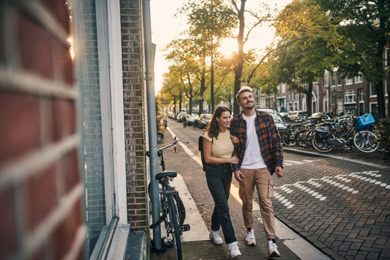 stel wandelt door Amsterdamse straat tijdens bezichtiging woning