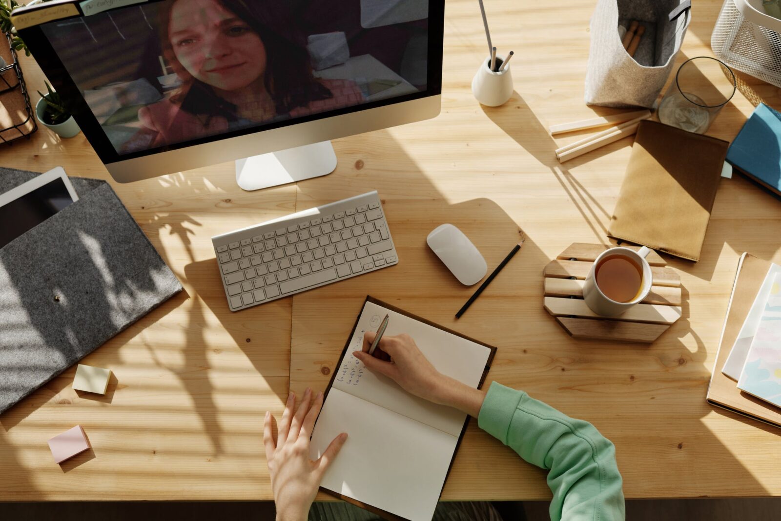 Overzicht van thuiswerkplek met bureau, computer, notitieboek en koffie in natuurlijk licht
