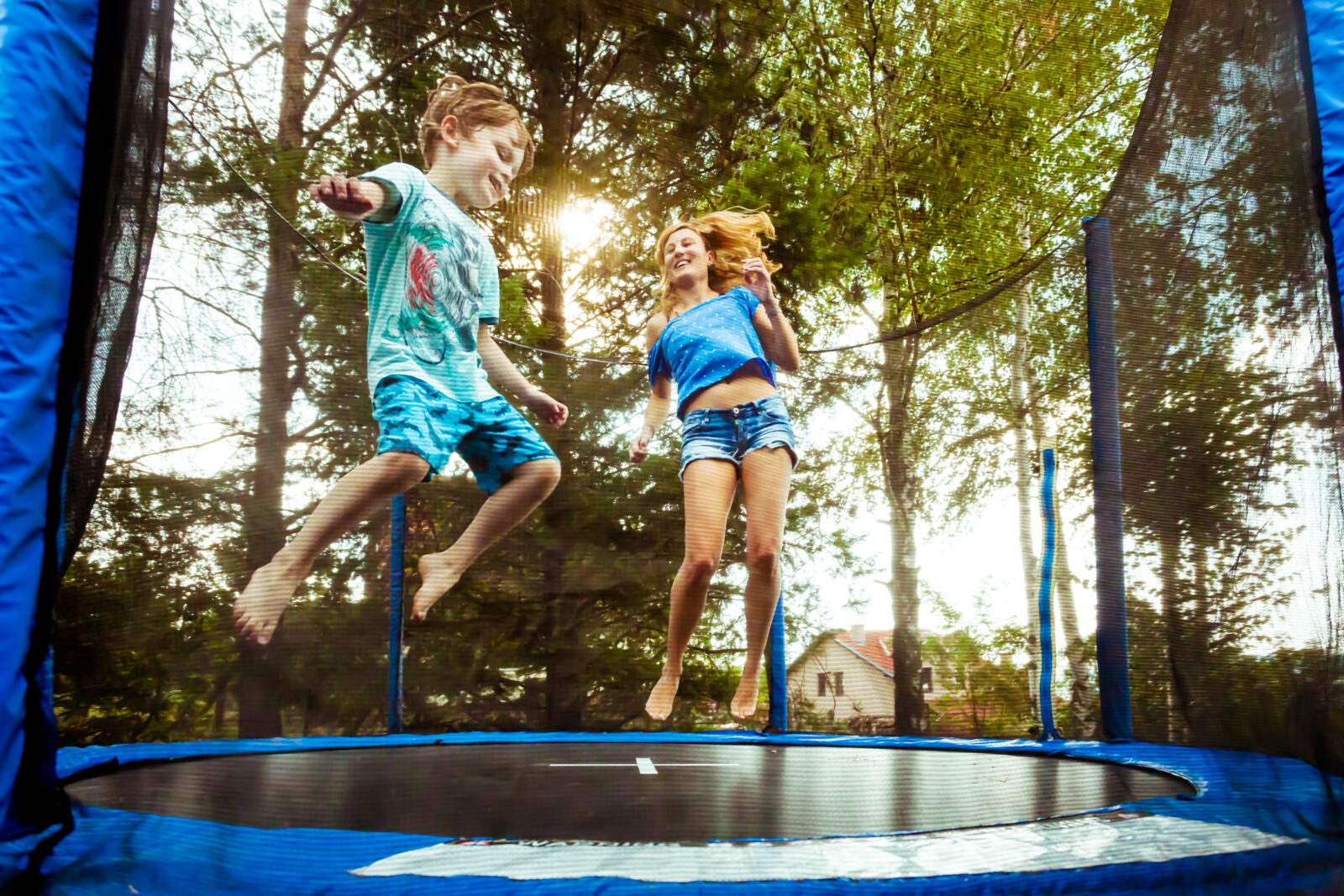 Kinderen springen samen op trampoline met veiligheidsnet in tuin