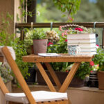 Klein balkon met houten tafeltje en stoel, omringd door planten en bloemen
