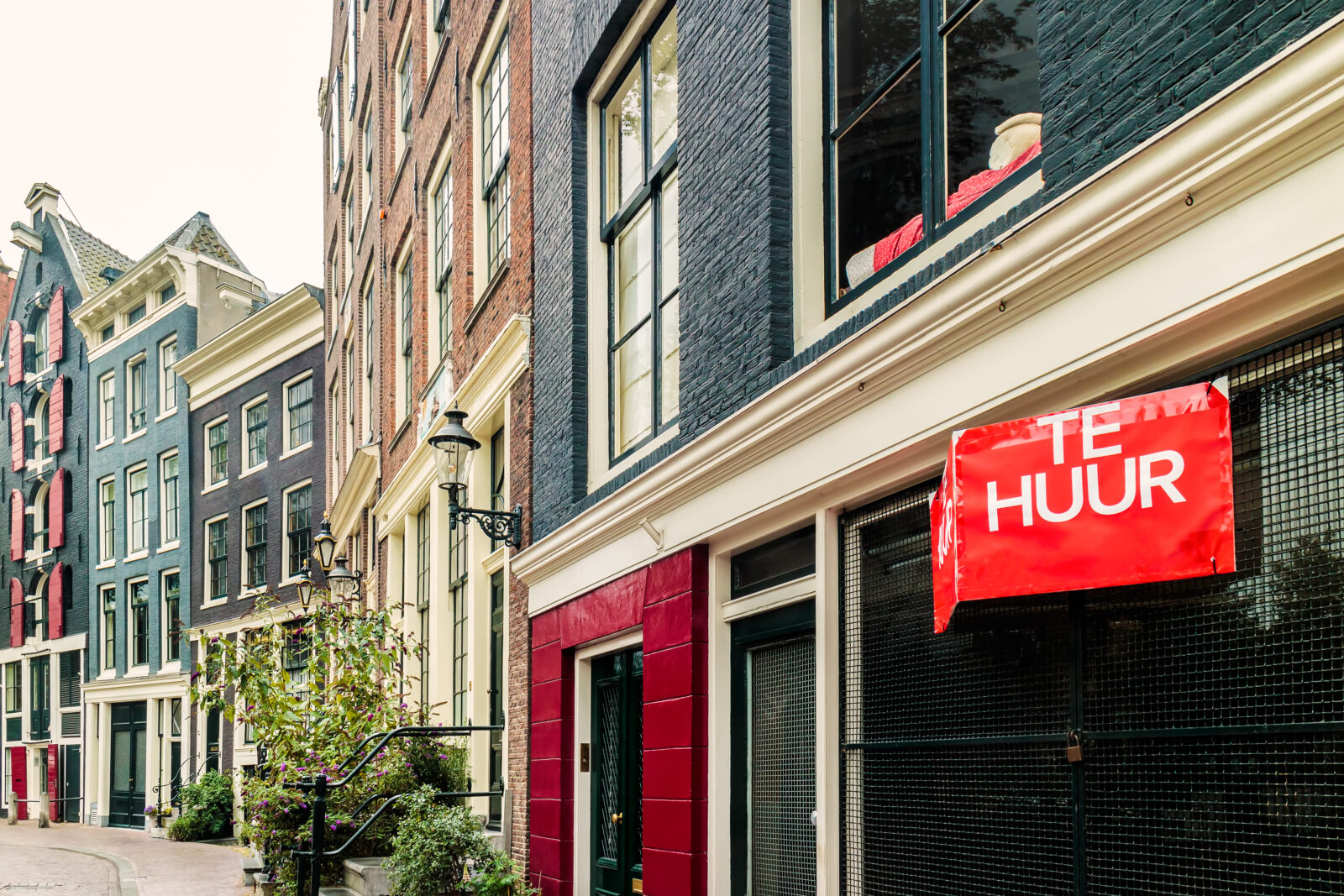 te huur bord aan woning in Nederlandse straat met huurwoningen