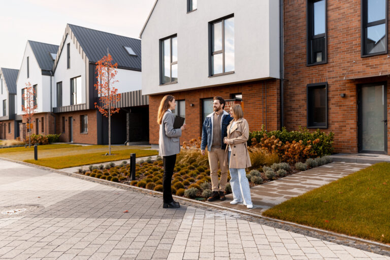 Stel bekijkt woning met makelaar in moderne woonwijk