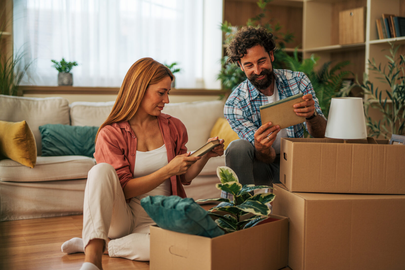 Stel pakt verhuisdozen uit in de woonkamer van hun nieuwe huis