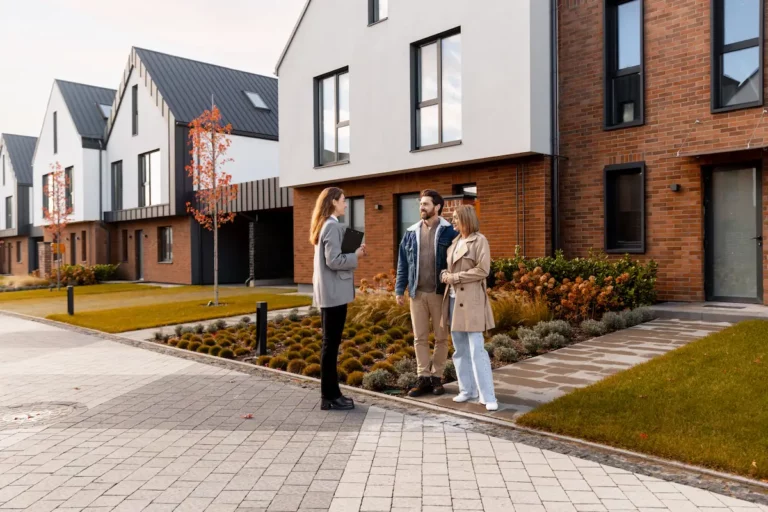 Stel bekijkt woning met makelaar in moderne woonwijk