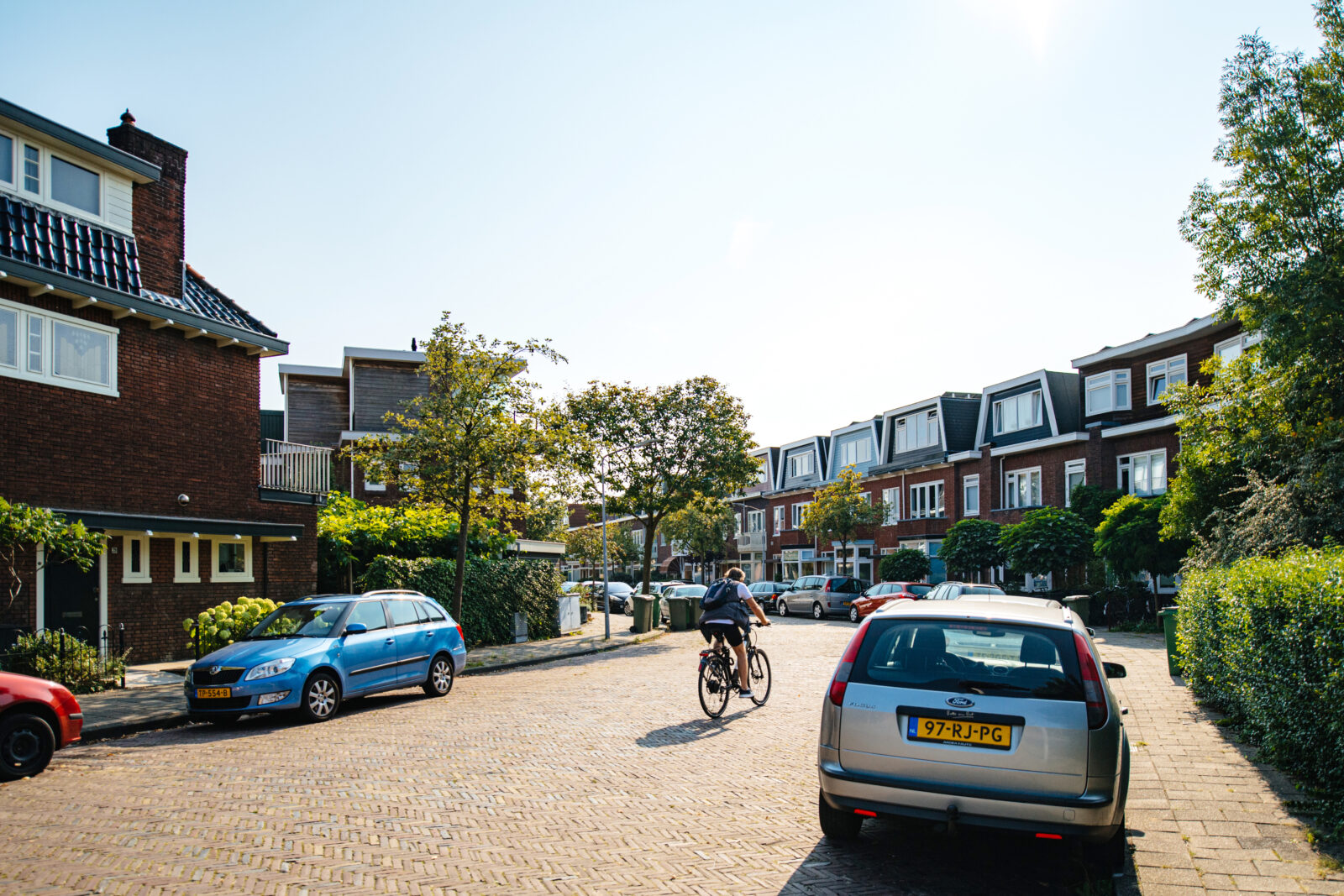 Rustige woonstraat in een Apeldoornse wijk met rijwoningen, geparkeerde auto’s en een fietser