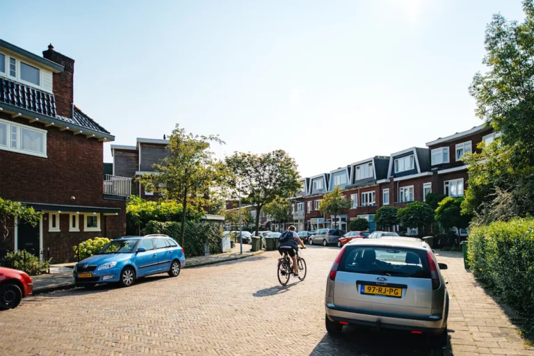 Rustige woonstraat in een Apeldoornse wijk met rijwoningen, geparkeerde auto’s en een fietser