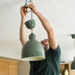 Man hangt een hanglamp op aan het plafond