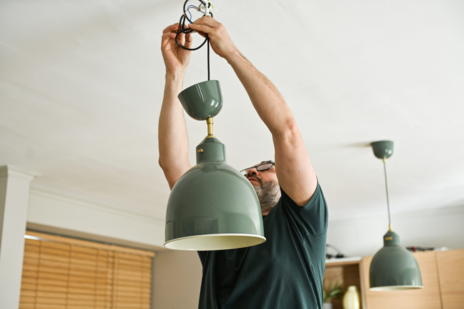 Man hangt een hanglamp op aan het plafond