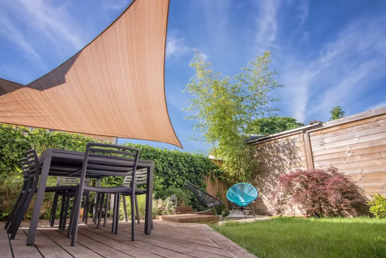 Schaduwdoek op maat boven een terras in een groene tuin