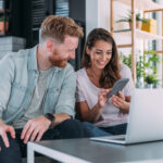 Stel bekijkt online woningaanbod op laptop en telefoon
