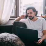 Zelfstandige voert thuis een zakelijk telefoongesprek met laptop op schoot