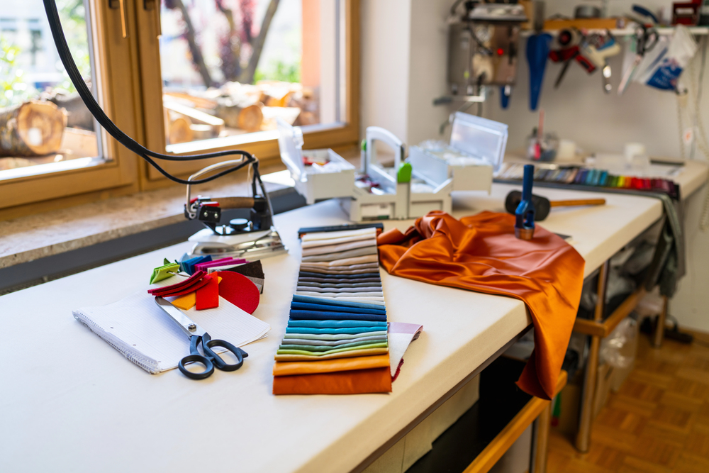 Werkblad in hobbyruimte met stoffen, schaar en kleurstalen bij het raam