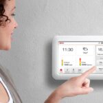Bewoner bekijkt energieverbruik op een slimme thermostaat