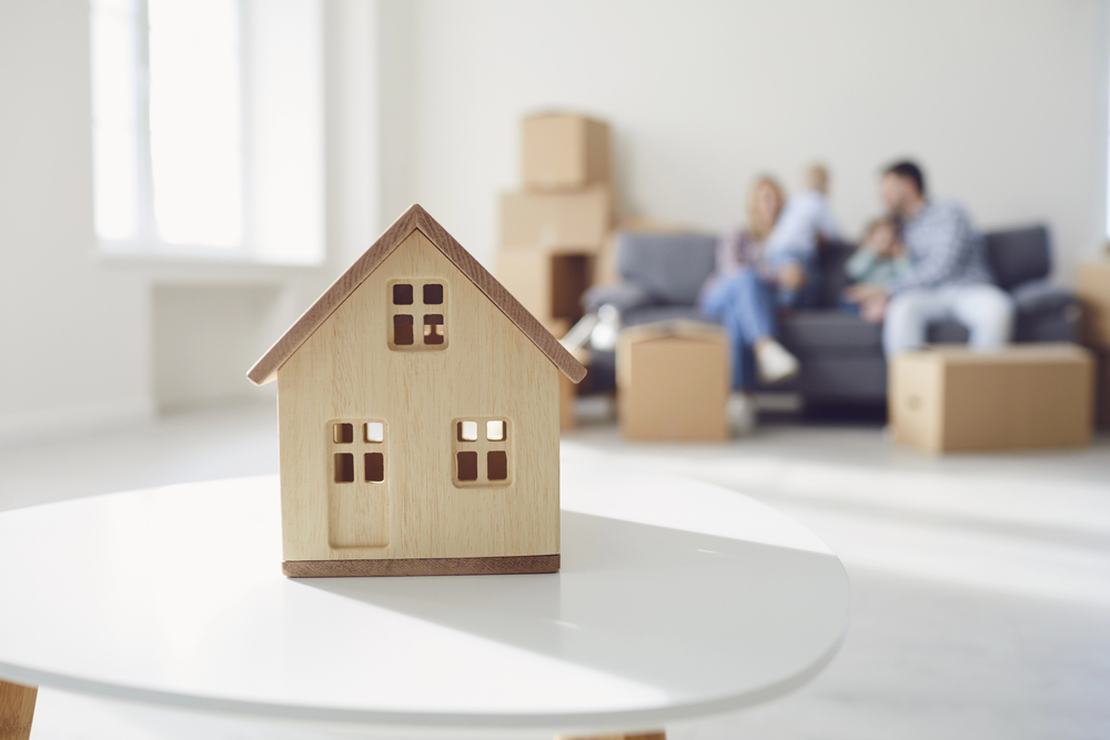 houten huisje met gezin en verhuisdozen als beeld bij verkoopstrategie huis verkopen