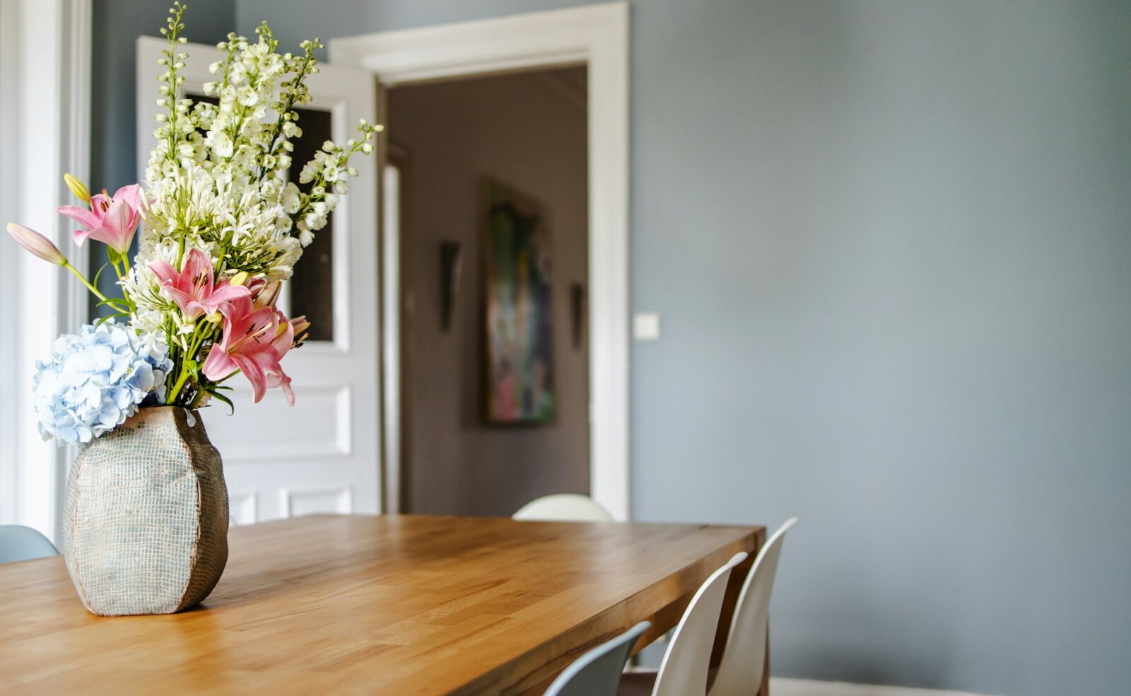 Hoog boeket bloemen in een vaas op een houten eettafel