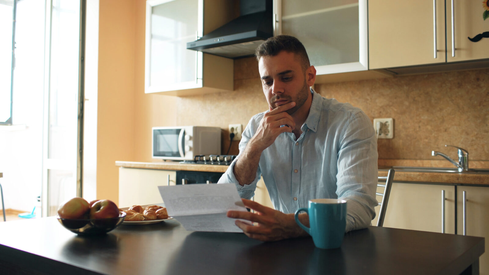Man leest thuis een brief aan de keukentafel