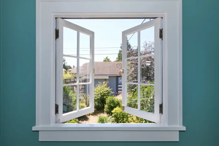 Openstaand wit raamkozijn met uitzicht op een groene tuin