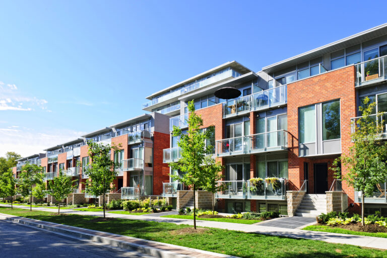 Modern appartementencomplex met balkons en bomen langs de straat.