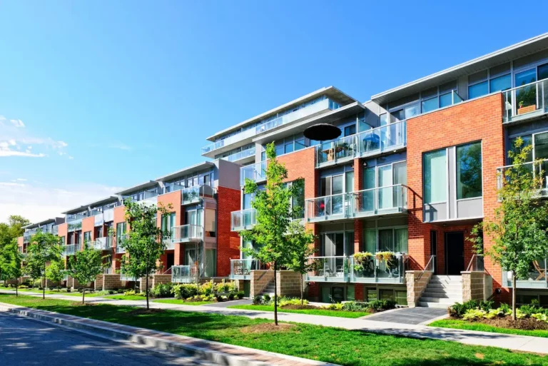 Modern appartementencomplex met balkons en bomen langs de straat.