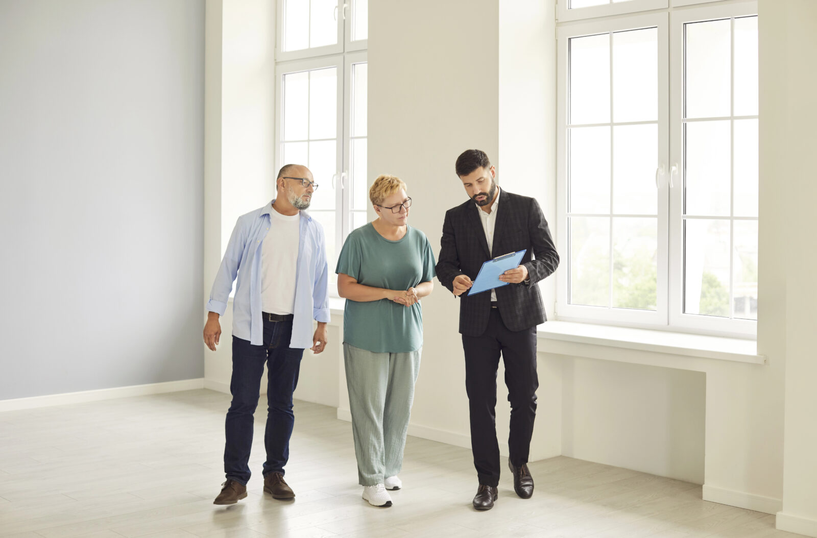 Potentiële kopers bespreken tijdens een woningbezichtiging informatie met de makelaar.